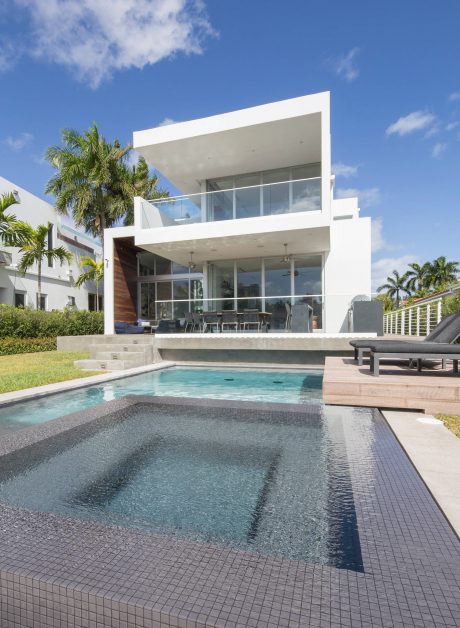 A modern, minimalist tropical villa with a sleek pool and expansive glass facade.