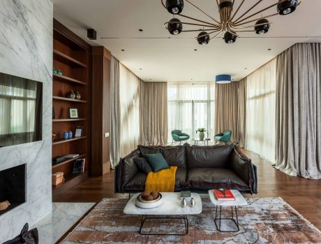 Elegant living room with marble walls, wooden shelves, and a modern light fixture.