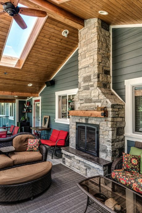 A cozy rustic interior with a stone fireplace, wood-paneled ceiling, and colorful accents.
