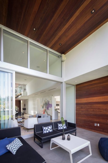 Spacious living area with high wooden ceiling, glass walls, and modern furniture.