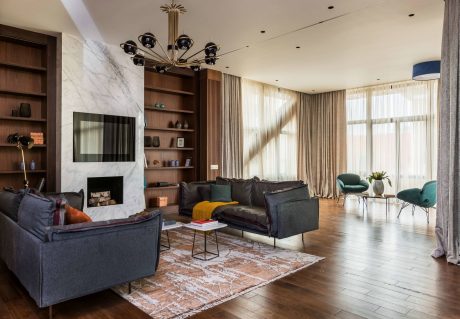 An elegant living room with a fireplace, built-in shelves, and a chandelier illuminating the space.