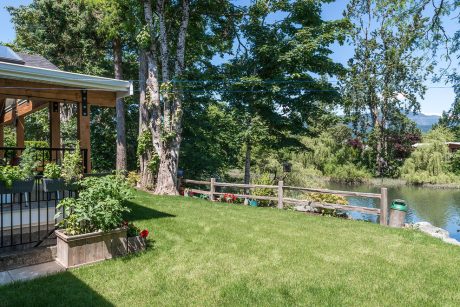 Cozy cabin porch overlooking lush green yard, pond, and wooded landscape.