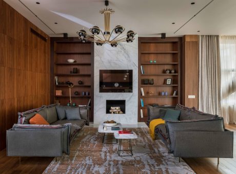 An elegant living room with a marble fireplace, built-in shelving, and a contemporary chandelier.