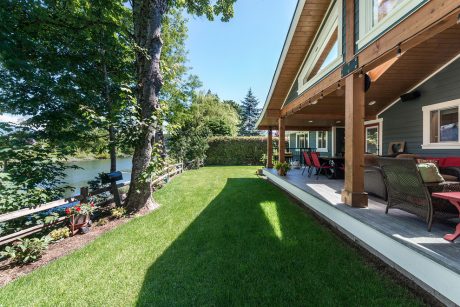 Inviting lakefront home with a cozy porch, lush greenery, and a well-manicured yard.