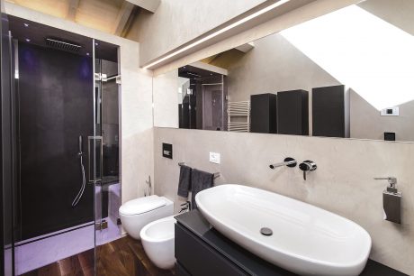 A modern, minimalist bathroom with sleek black and white fixtures, a large shower, and floating vanity.