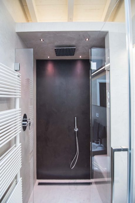 Modern shower enclosure with sleek black tiling, recessed lighting, and shower head.