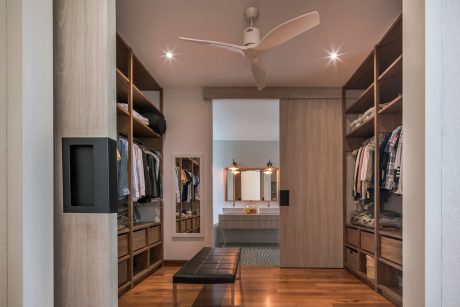 A spacious walk-in closet with wooden shelves, a vanity, and a ceiling fan.