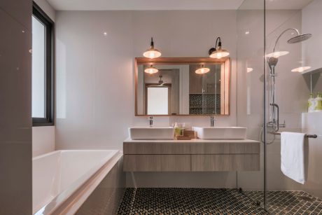 A modern bathroom with a double vanity, large mirror, and a tiled hexagonal floor pattern.