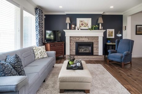 Warm, inviting room with stone fireplace, plush couch, and blue accent chair on hardwood floors.
