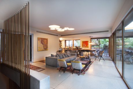 Spacious modern living room with wooden screen divider, pendant lights, and outdoor patio.