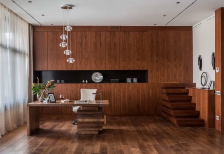 Elegant interior with rich wood paneling, modern pendant lights, and a striking staircase.