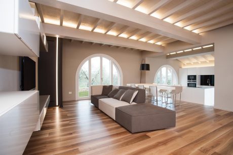 Spacious modern living room with arched windows, wooden beams, and a large sofa.