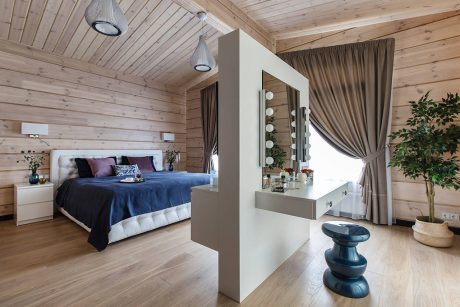 Cozy wooden cabin bedroom with plush bedding, sleek vanity, and modern lighting fixtures.