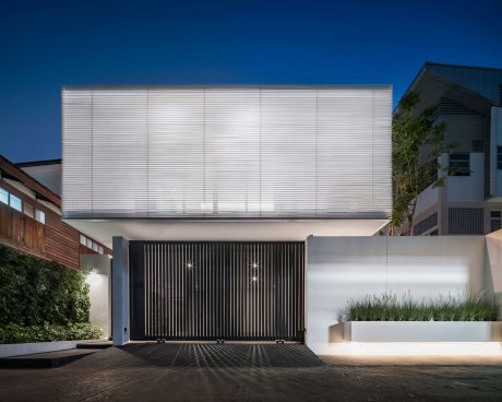 Sleek, modern architecture with a striking black gate, white facade, and lush greenery.