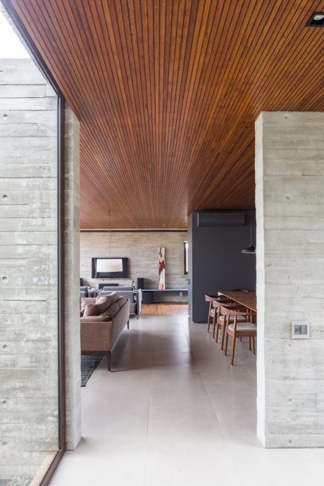 Warm wooden ceiling, concrete walls, and minimalist furnishings create a cozy, modern atmosphere.