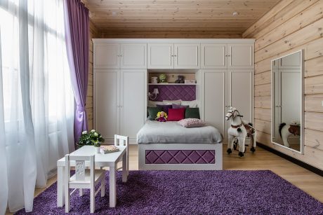 Cozy wooden room with built-in wardrobe, plush purple carpet, and bright natural lighting.