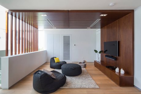Modern living room with sleek wood paneling, minimalist furniture, and recessed lighting.