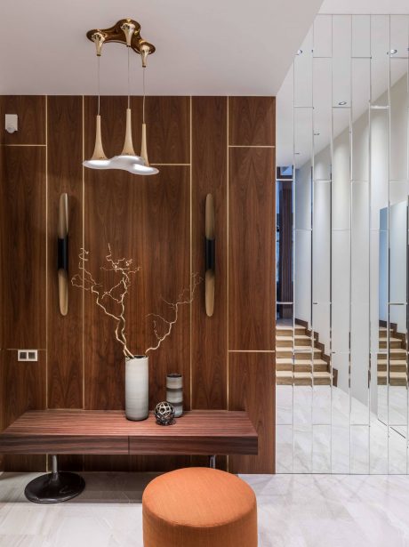 Modern entryway with sleek lighting fixtures, wooden paneled walls, and a decorative bench.