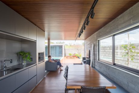 A modern open-plan kitchen and living area with wooden accents and large windows.