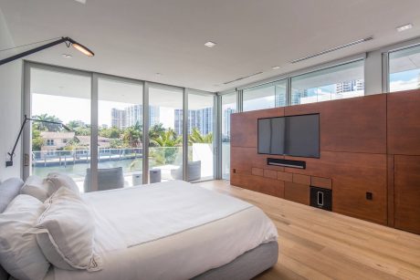 Spacious bedroom with floor-to-ceiling windows, wooden feature wall, and modern furnishings.