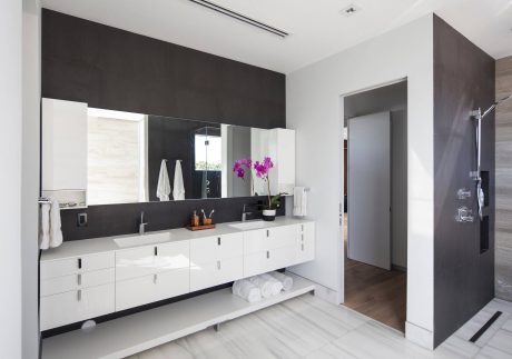 Sleek, modern bathroom with white cabinetry, dark accent wall, and minimalist fixtures.