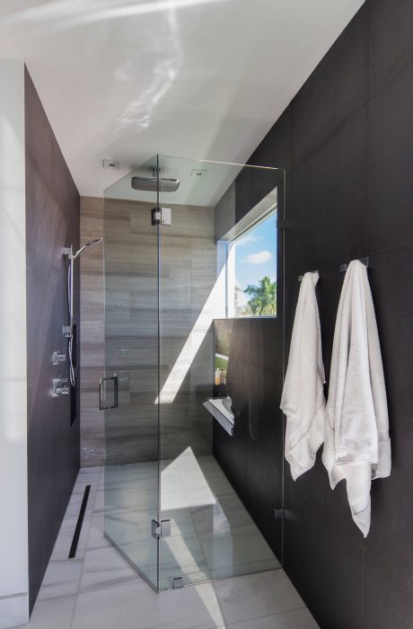A modern, sleek bathroom with a spacious glass shower enclosure and recessed lighting.