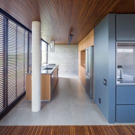 The image showcases a modern kitchen with concrete walls, wooden ceiling, and sleek appliances.