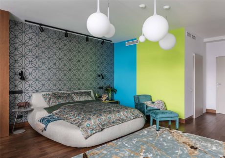 Vibrant color scheme, geometric wallpaper, and unique lighting fixtures in modern bedroom.
