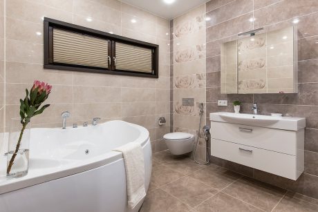 Spacious modern bathroom with a freestanding tub, vanity, and tiled walls featuring floral patterns.