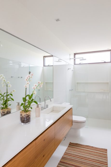 Sleek, modern bathroom with wood vanity, white countertop, and potted orchids accenting the space.
