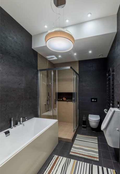Sleek, modern bathroom with a circular light fixture, glass shower, and patterned tile floor.