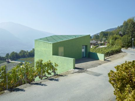 A modern, green-colored building with geometric patterns on the roof and a distinctive entrance.