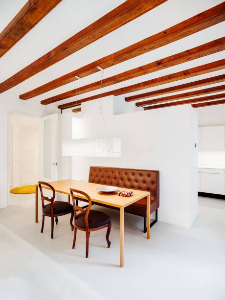The dining area features a wooden beamed ceiling, tufted leather bench, and modern dining table with chairs.
