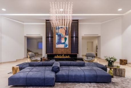 Luxurious living room with ornate crystal chandelier, marble fireplace, and plush navy sofa.