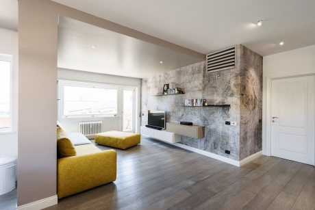 Open-concept living room with modern gray and yellow decor, wood floors, and built-in media unit.
