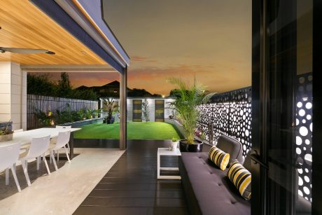 Contemporary outdoor living space with modern patio furnishings, lush landscaping, and striking lighting features.