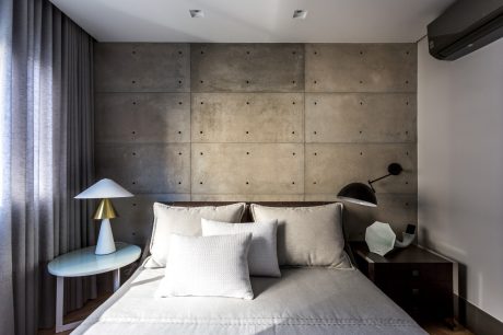 Minimalist concrete-paneled bedroom with modern lighting and furniture.