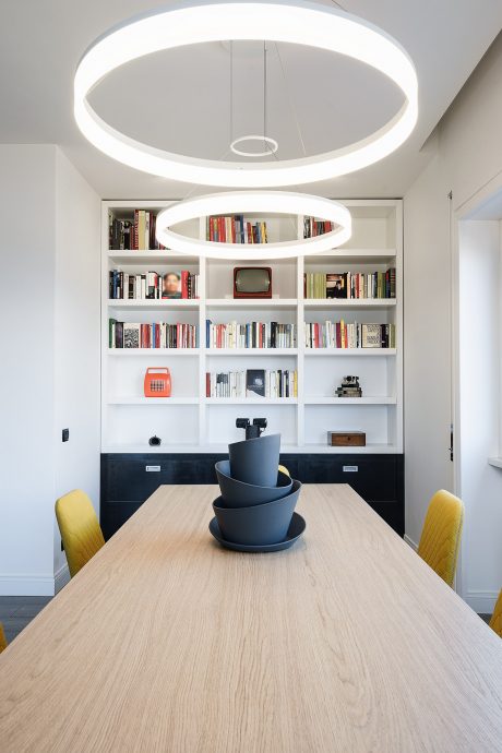 Minimalist dining room with circular pendant lights and built-in bookshelves.