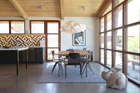 Rustic modern dining area with wooden ceiling, black furniture, and geometric backsplash.