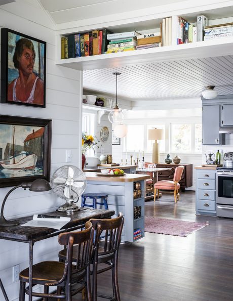 Cozy kitchen nook with open shelving, diverse artwork, and retro furnishings.