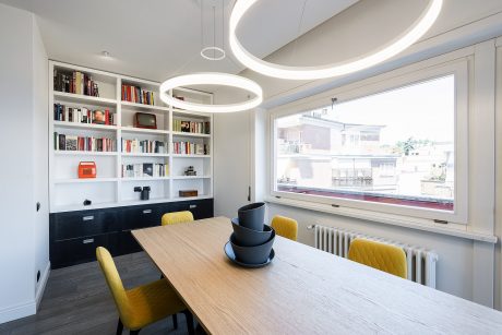 Spacious, modern dining room with circular lighting fixtures, built-in shelves, and large window.