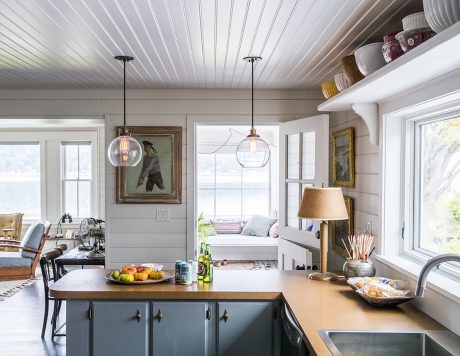 Cozy kitchen with farmhouse-style decor, wooden beams, and pendant lighting above island.