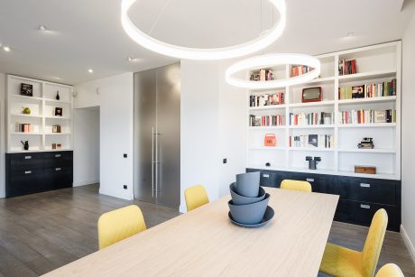 A modern, minimalist open-plan living space with custom built-in shelves and lighting.
