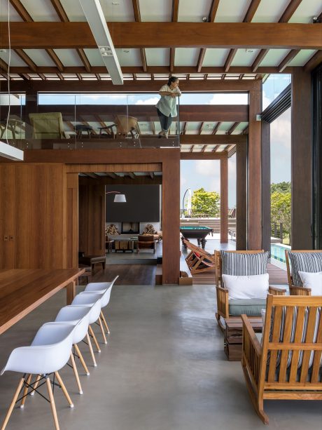 A modern, open-concept living space with wooden beams, glass walls, and cozy furnishings.