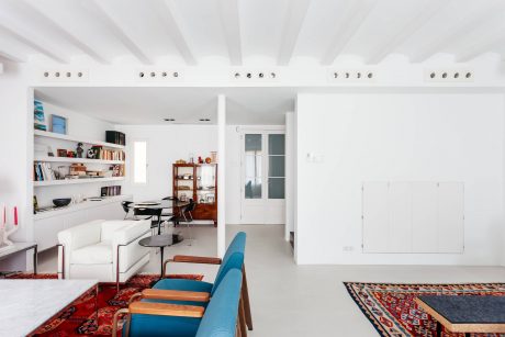 Bright, minimalist interior with white walls, exposed beams, and colorful furnishings.