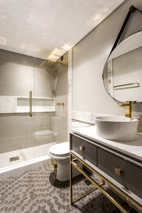 Stylish bathroom with sleek white fixtures, brass accents, and geometric tile flooring.