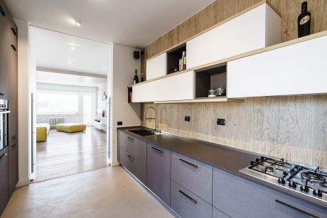 A modern kitchen with wood-paneled walls, sleek cabinets, and a stainless steel sink.