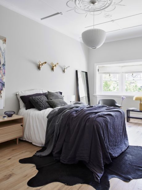 Cozy bedroom with textured bedding, wood furniture, and ornate ceiling decor.