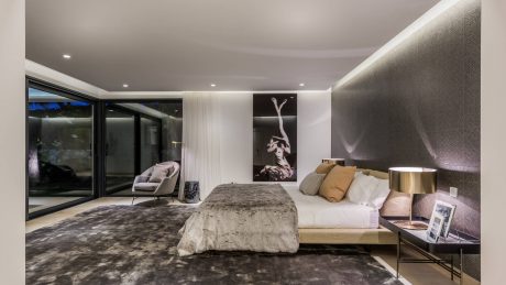 Luxurious modern bedroom with large bed, plush rug, and striking artwork on the walls.