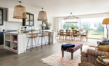 Spacious open-concept kitchen with large windows, woven pendant lamps, and a rustic wood dining table.